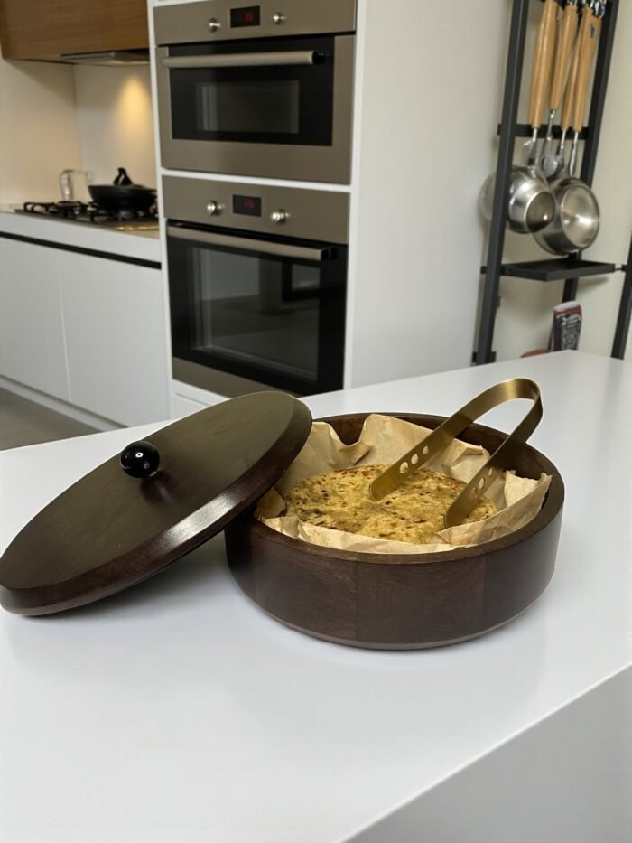 "- Premium Mango Wood – Handcrafted from seasoned mango wood with a polished finish, offering durability and a rich natural grain - Natural Heat Retention – Dense wood construction keeps rotis, chapatis, and tortillas warm and fresh for longer - Secure Wooden Lid with Knob – Ergonomic lid ensures freshness while providing an easy grip for serving - Multi-Purpose Storage – Ideal for rotis, parathas, tortillas, bread, or as a serving bowl for snacks and dry foods